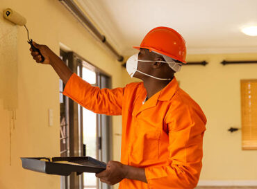 professional african construction worker painting the wall